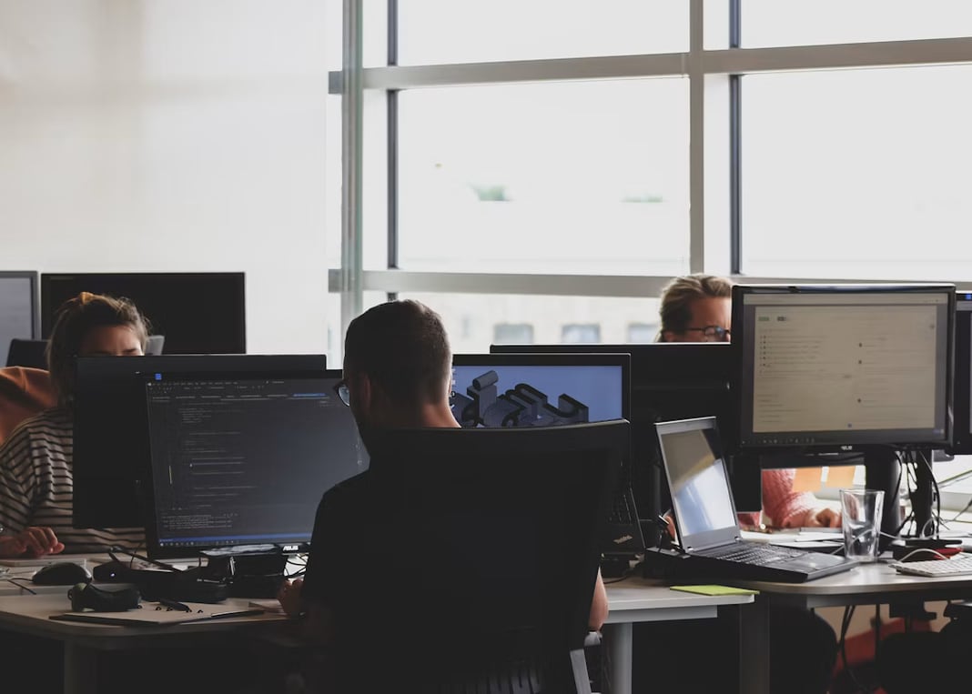 Engineers at their desks, working at screens of code