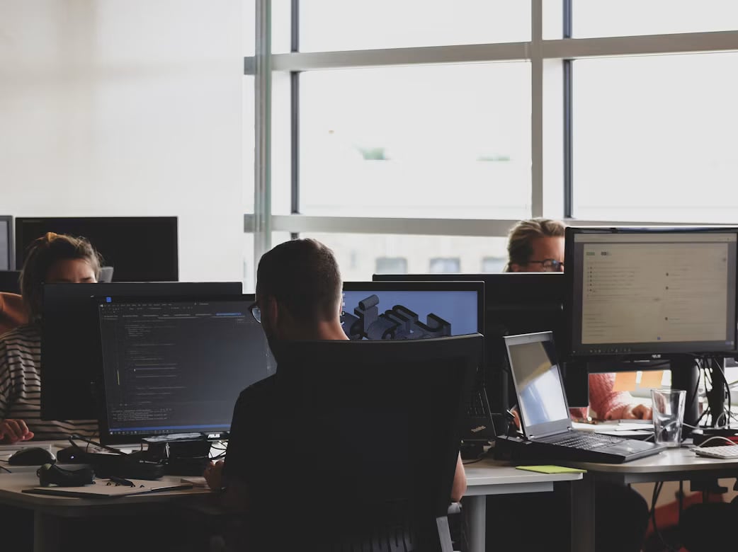 The studio at work: desks, monitors and code on screen